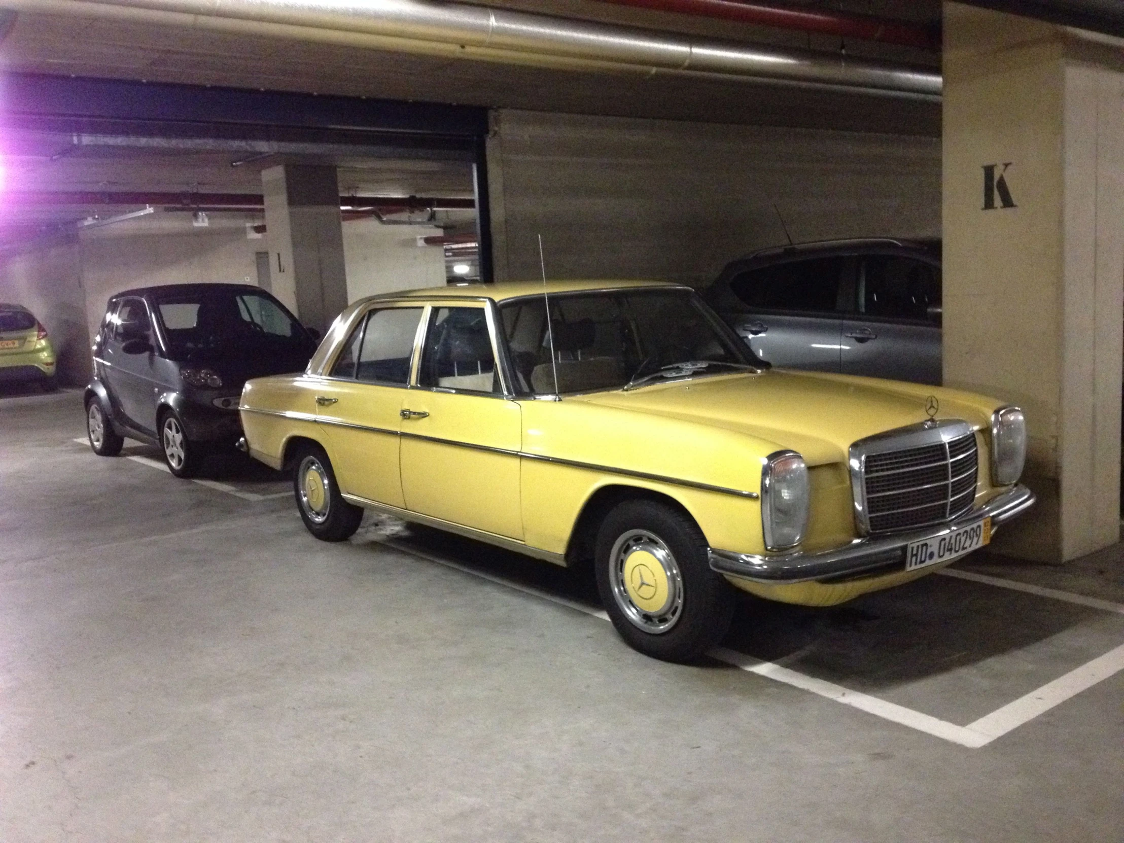 an old yellow car is parked in the parking garage