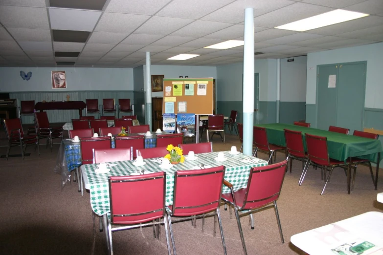 an empty classroom with tables and chairs filled with green cloth