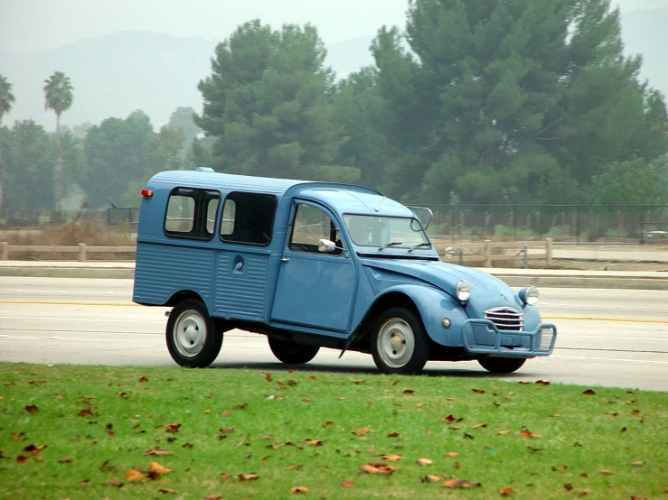 a blue, two - wheeled car drives down the road