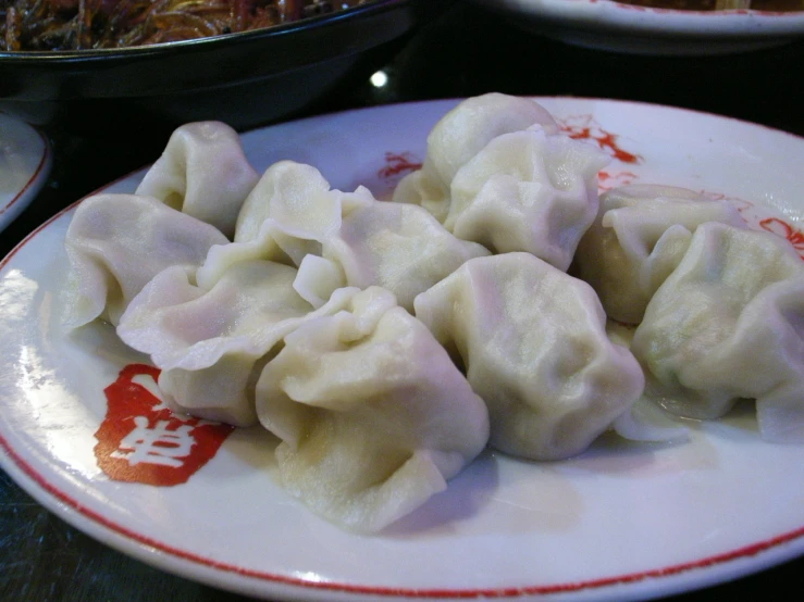 a white plate with dumplings on it and sauce