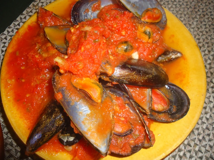 a plate of food sitting on a table with a bowl of mussels and some other ingredients