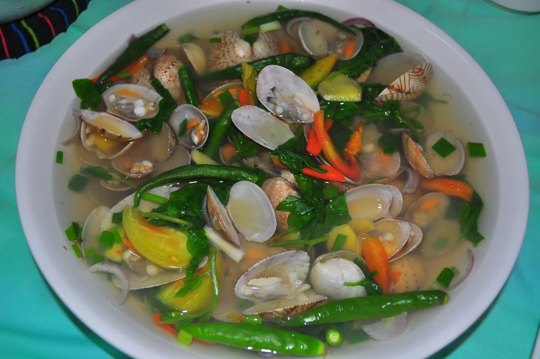 a bowl filled with steamed shrimp, shellfish, peppers and mushrooms