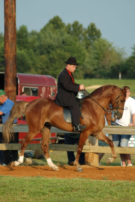 man on a horse next to a wooden fence in front of several people