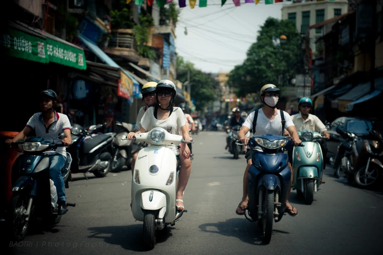 two women on motor bikes riding down the street