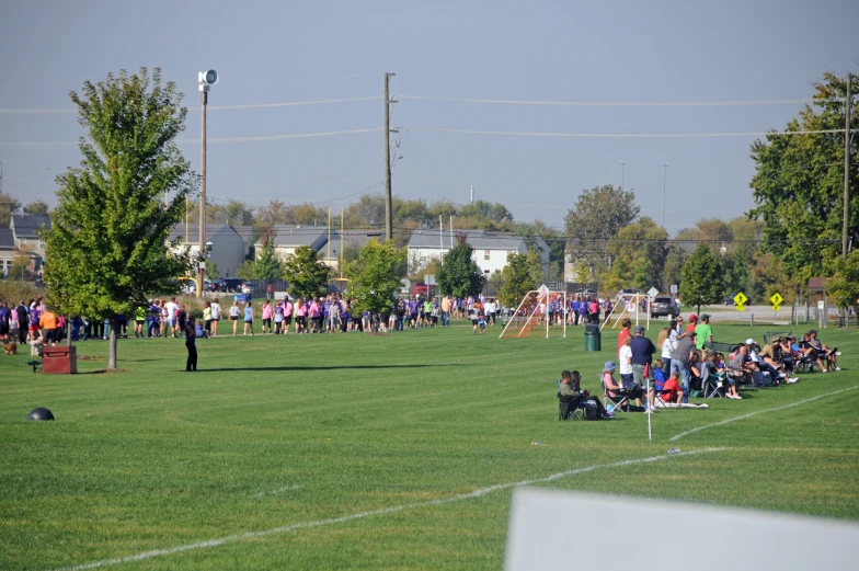 there are some people sitting on the grass at a game