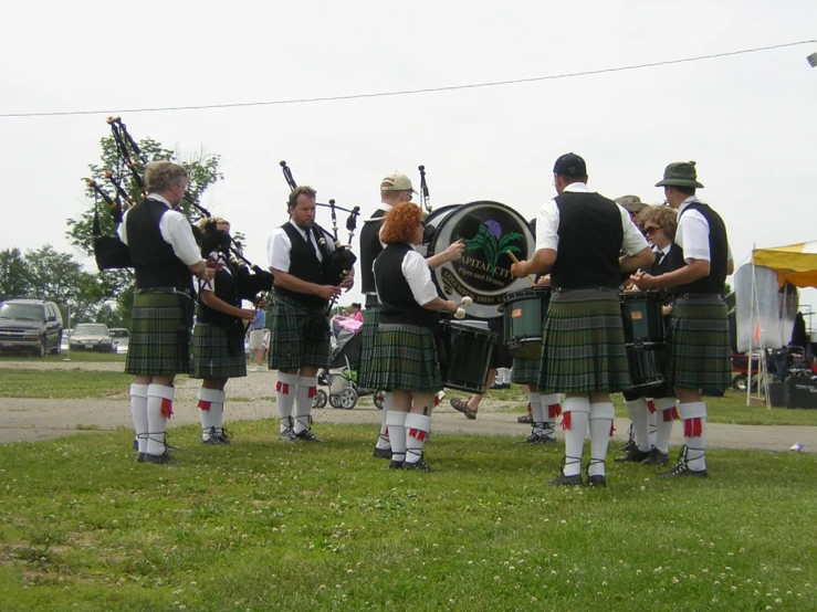 four men are dressed in a kilt and one is holding a bagpipe