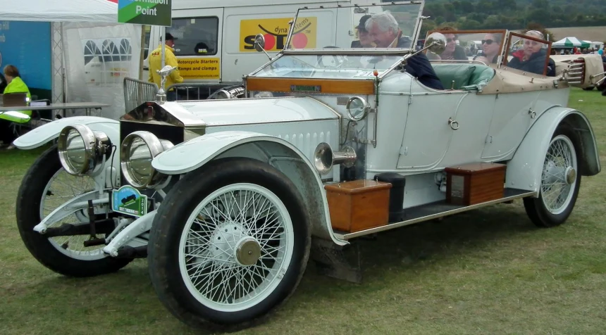 a white old model automobile on display on the grass