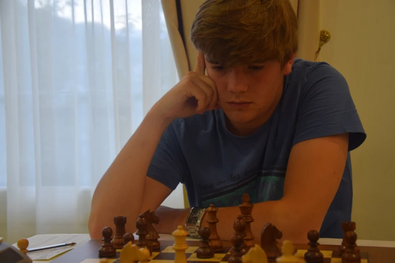 the young man is looking at a chess game