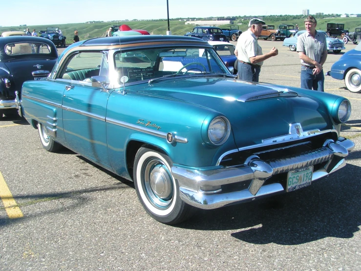 an older man and older woman admiring the vintage car