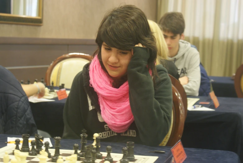 a girl in pink scarf playing chess