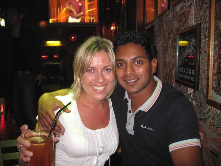 a young man and woman holding drinks while standing together