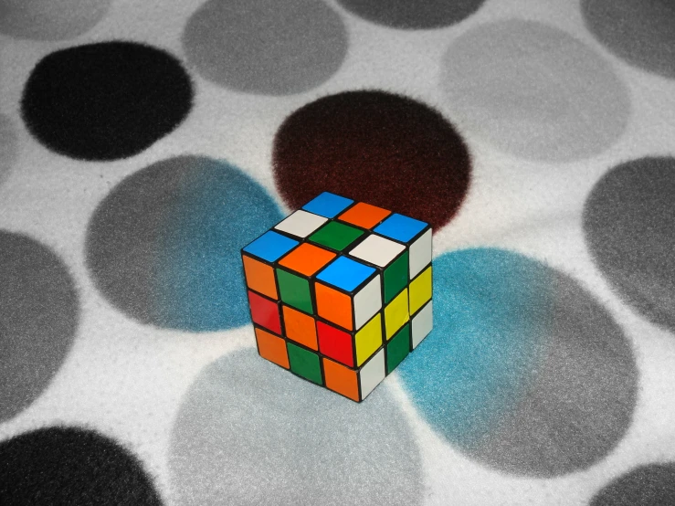 a colorful cube is on the ground near grey circles