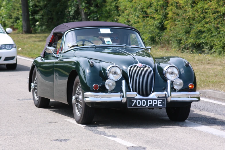 a green vintage car on the side of a road