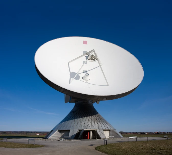 an enormous satellite dish sits on display in the middle of a field