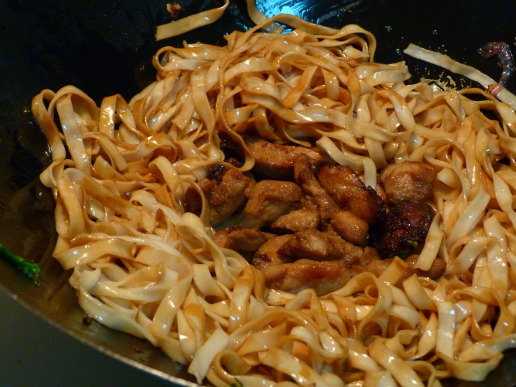 noodles, chicken and mushrooms cooking on a wok