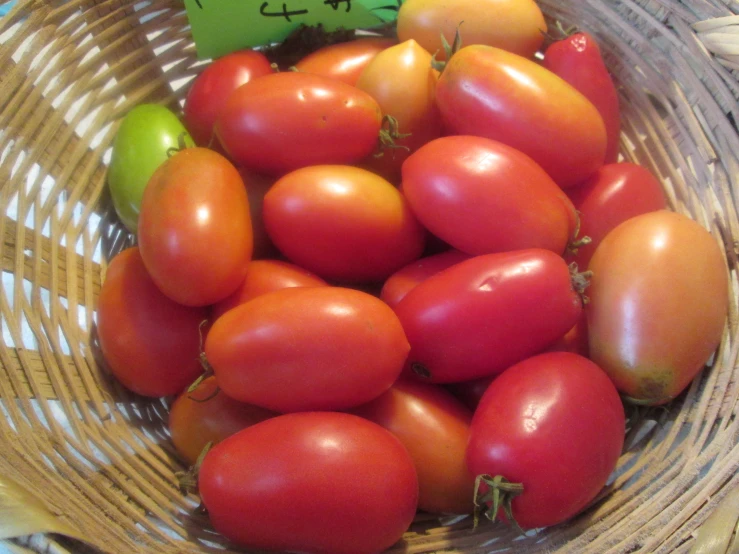 the basket has tomatoes and a green apple in it