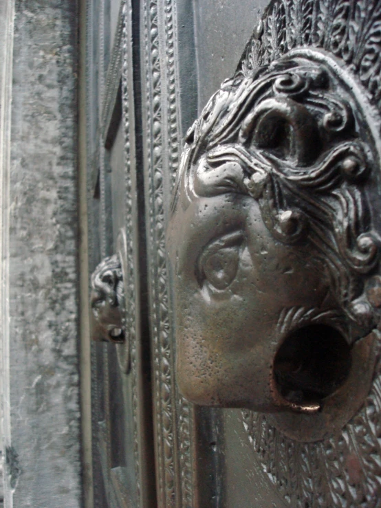 a door knockner has intricately carved faces