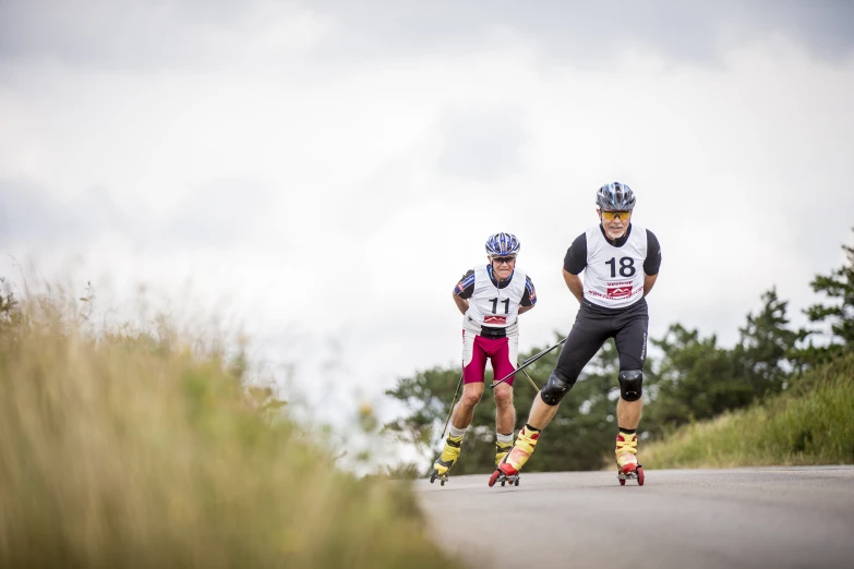 two people on skateboards riding down a road