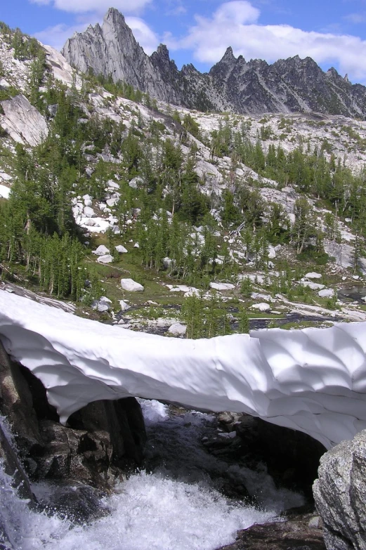 a bridge covered in snow next to a creek