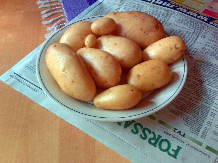 the bowl of potatoes has been placed on the newspaper