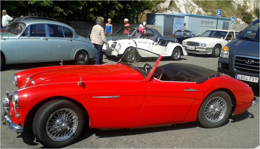 a red vintage car parked in front of other classic cars