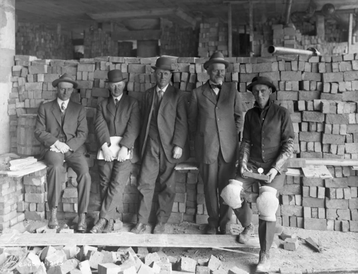 a black and white image shows men working at brick walls