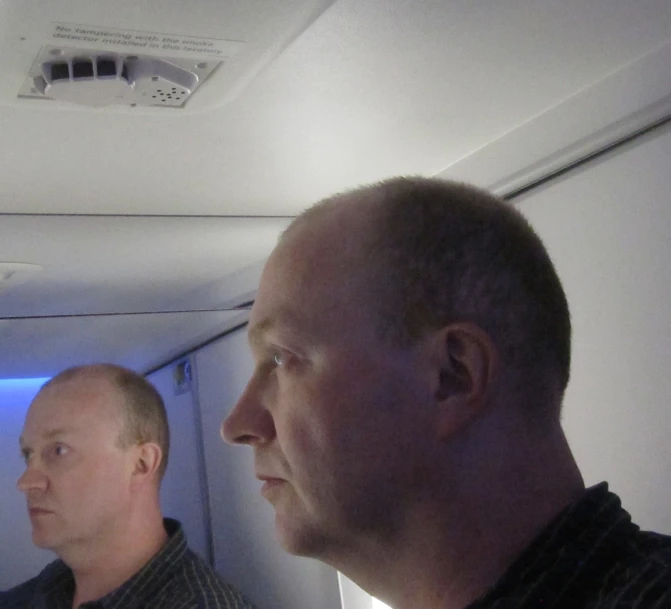 two men standing in an airplane while looking at the sky