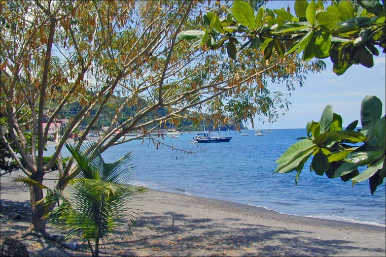 an empty beach is shown with boats in the water