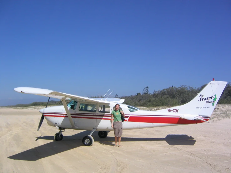 a person standing beside a plane on the beach