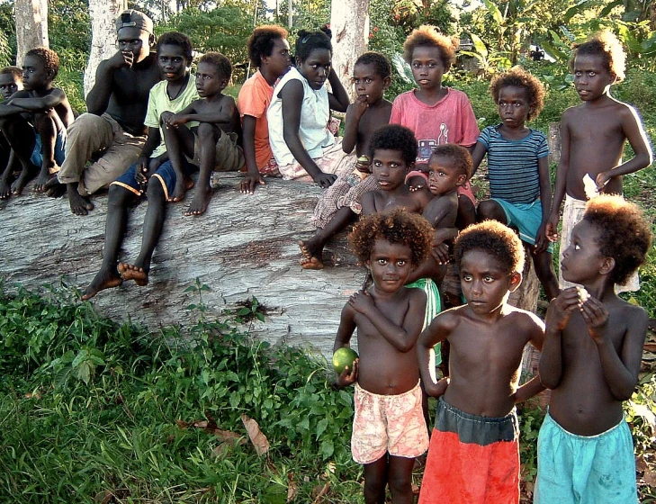 several children and adults are gathered in the woods