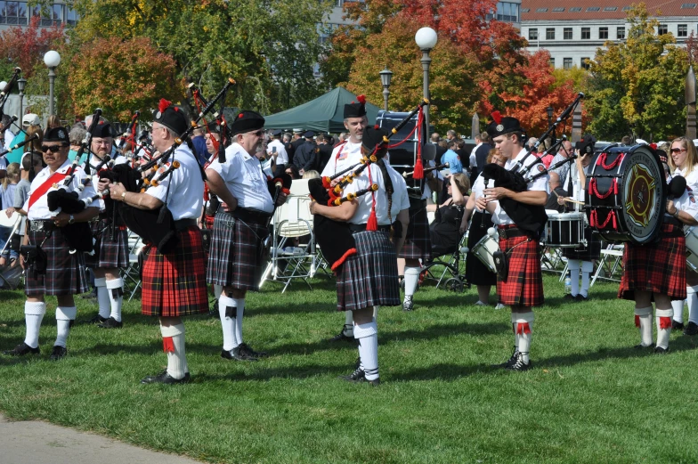 a line of men and women in a row playing bagpipes