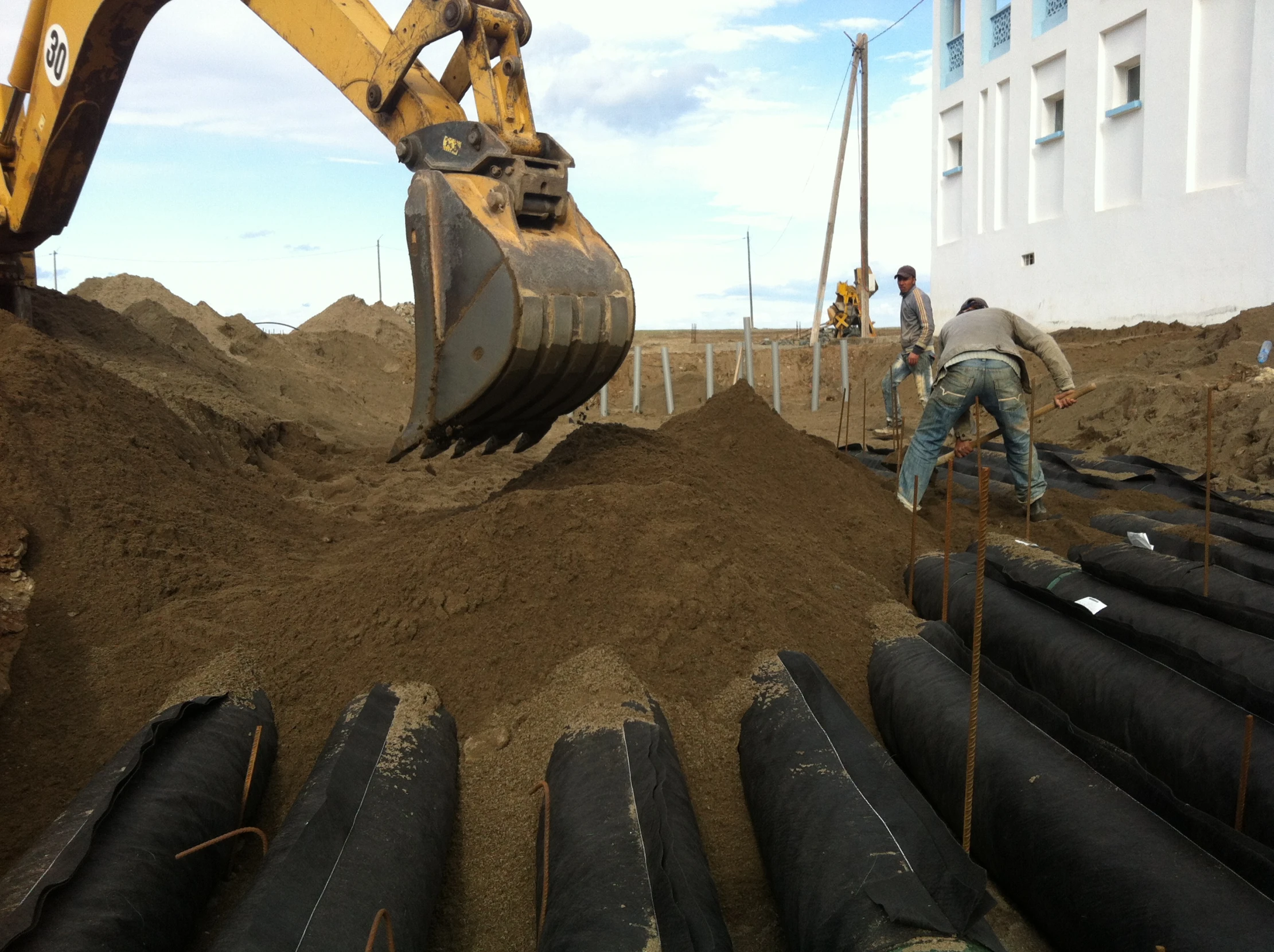 two men are digging the earth into some black pipes