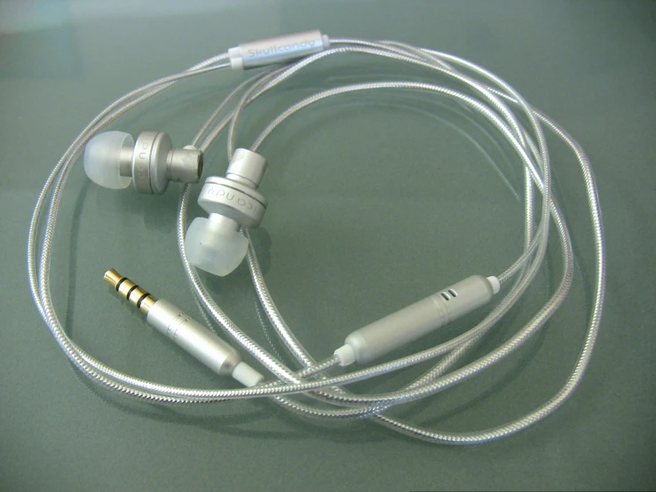 two headphones on a table with a silver cord