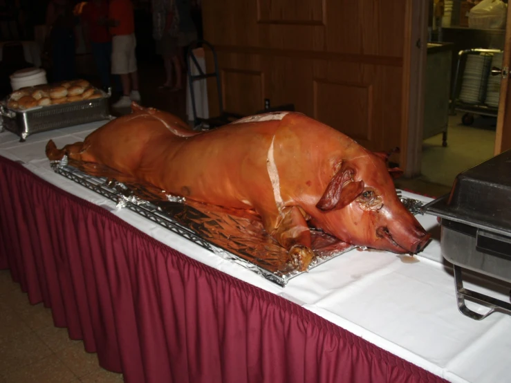 a fake pig laying on a metal pan next to other food items