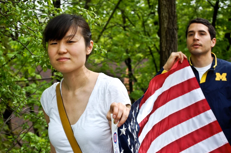 a young man and woman holding an american flag