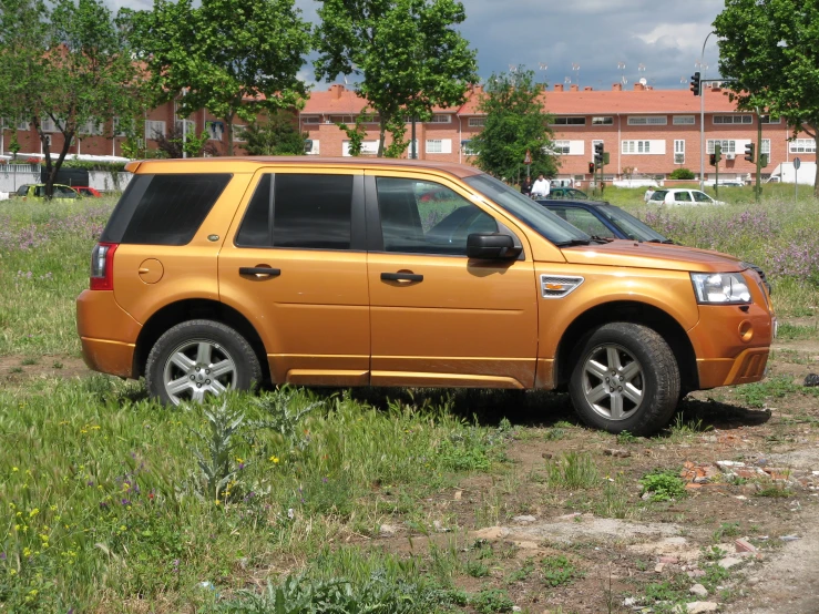 a yellow four door suv parked in front of some brown brick houses