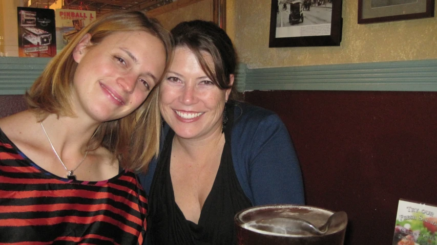 two women sitting together at a table smiling