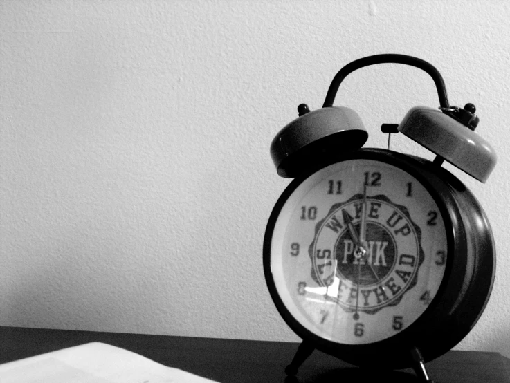 a black and white picture of an alarm clock on a table