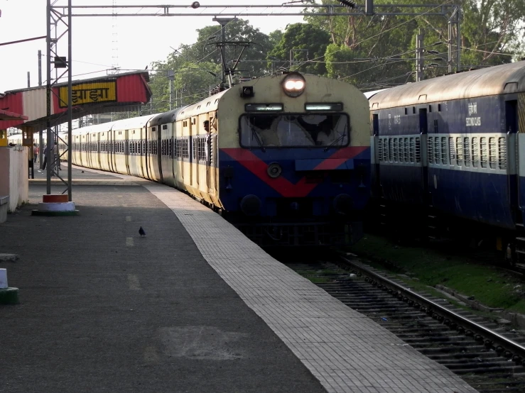 a blue and white train sitting next to a green building