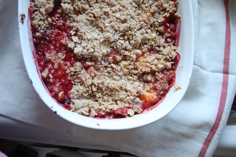 a bowl of fruit crumb covered with soing else