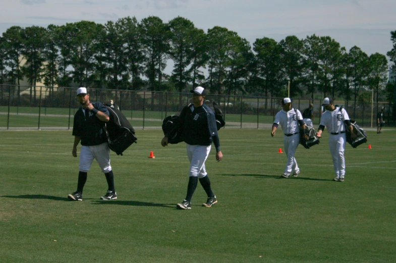 the baseball players are all carrying bags