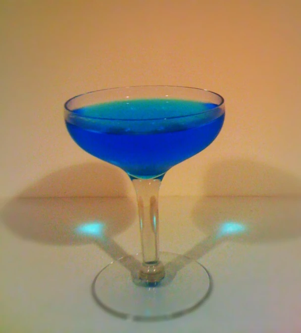 a blue drink in a glass on a white table