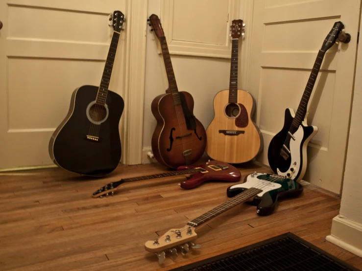 guitars are arranged in a line on a wooden floor