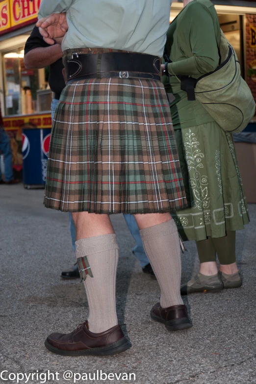 two men wearing scottish clothes are standing side by side
