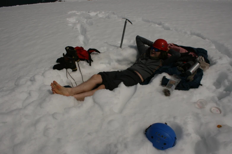 man sleeping in the snow with two shovels