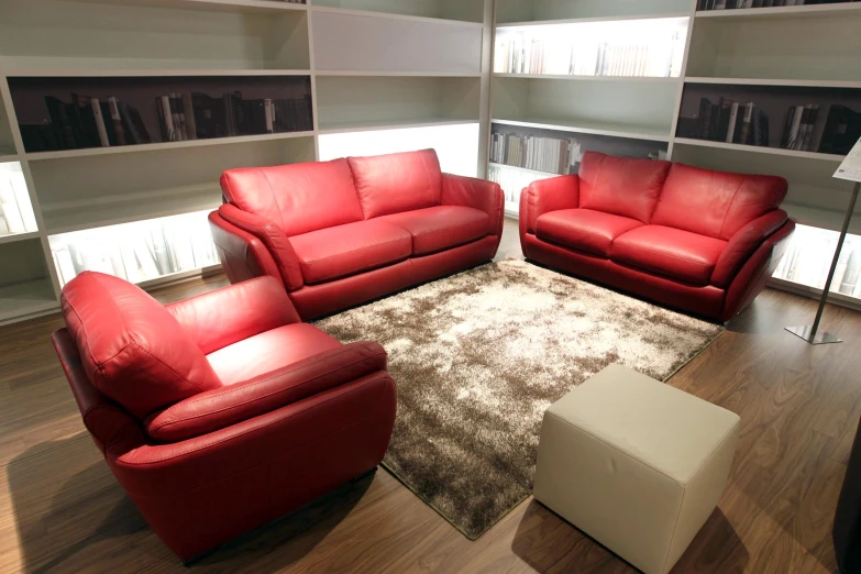 a living room with red leather couches on top of a rug