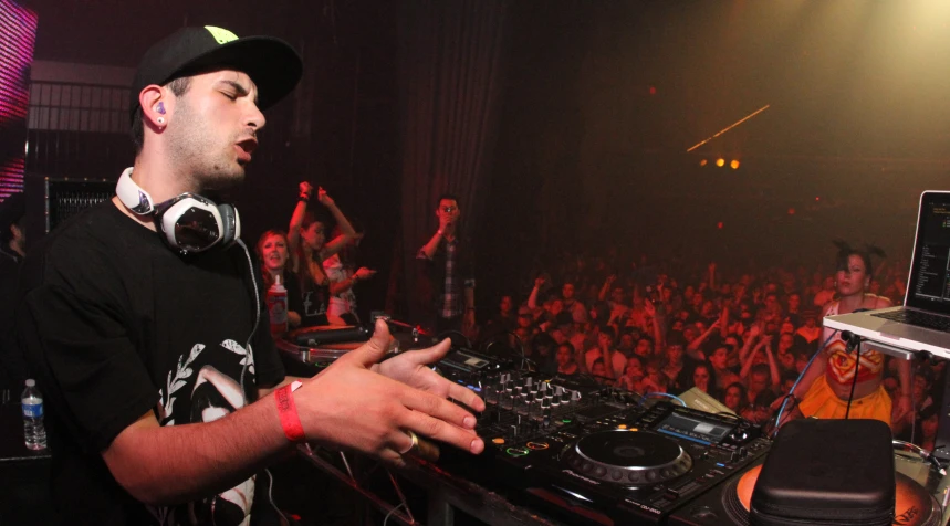 dj in a crowd, with headphones on his ears, operating a record player