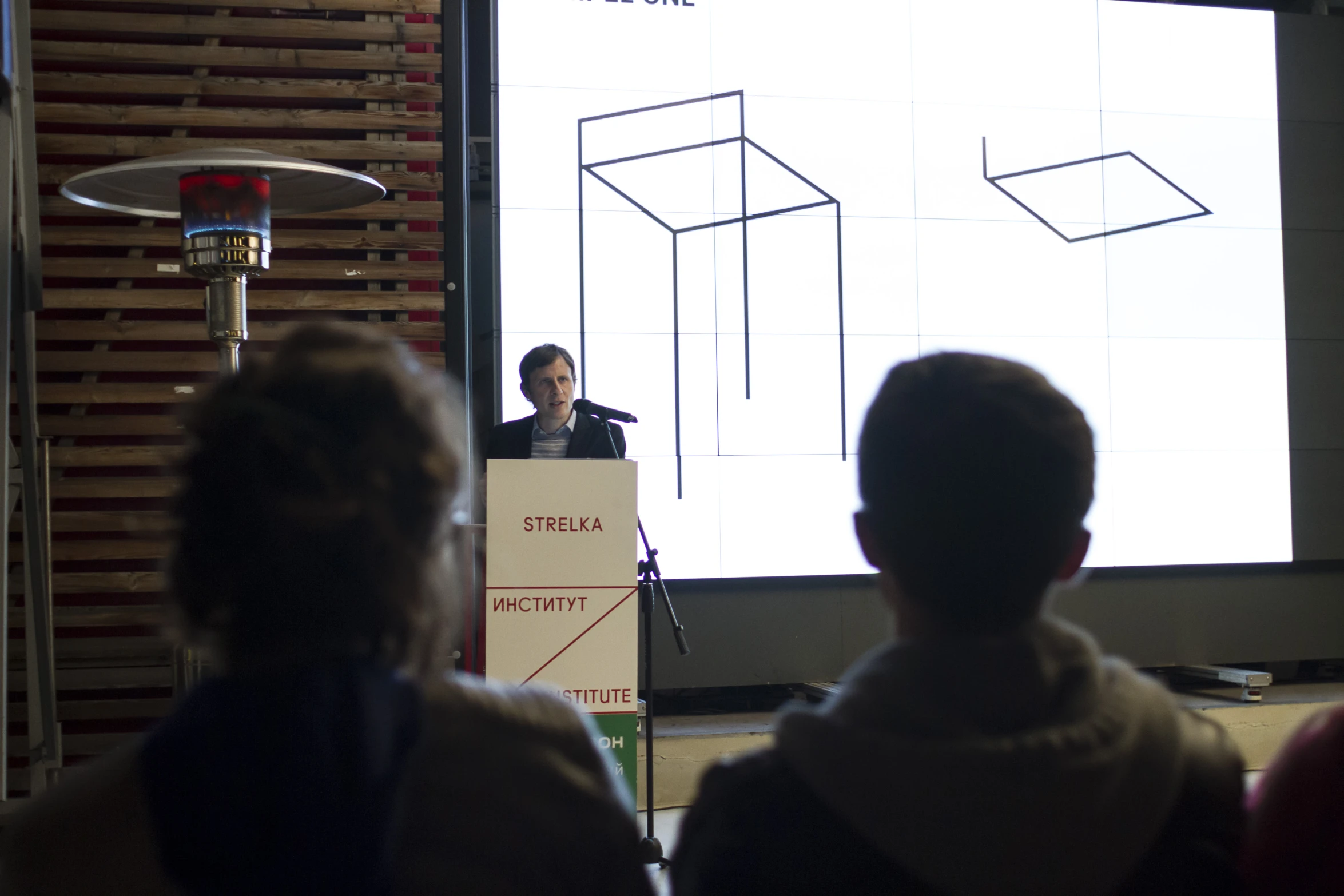 a woman giving a lecture to people in front of a screen