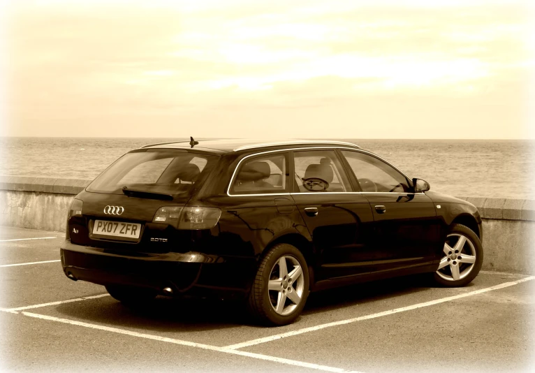 an black car parked by the water in the parking lot