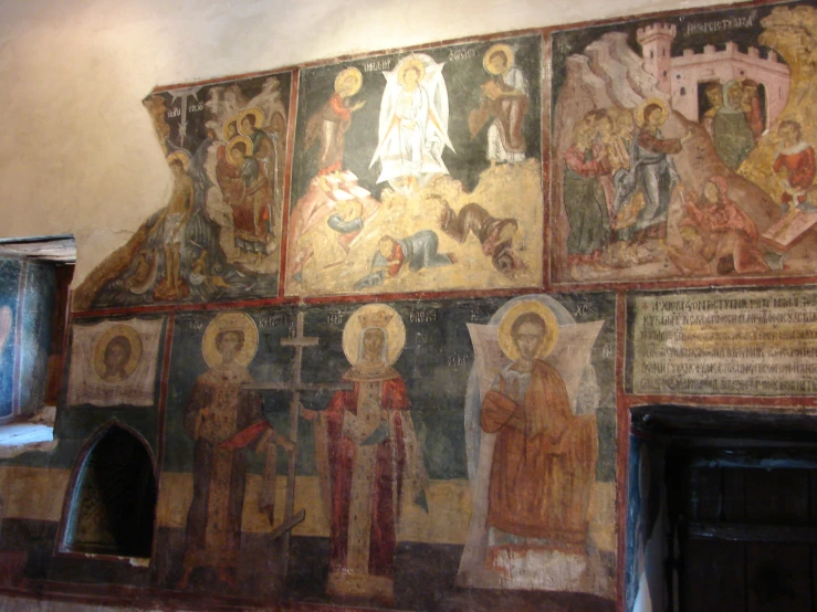 a wall covered in ornate murals next to a doorway